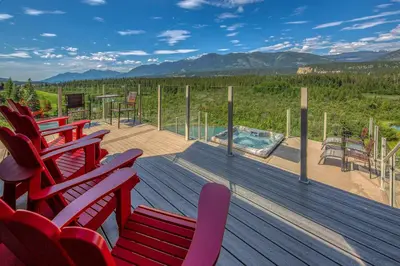 a deck with red chairs and a swimming pool at CLIFF CABIN Family Friendly|Hot Tub|Spectacular Views in Fairmont Hot Springs