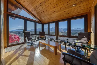 a living room with a table and chairs and windows at CLIFF CABIN Family Friendly|Hot Tub|Spectacular Views in Fairmont Hot Springs