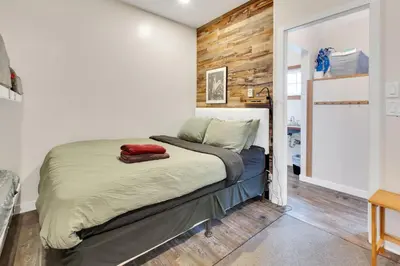 a bedroom with a bed with a wooden wall at Grey Whale, Pet Friendly Studio at The Beach in Ucluelet
