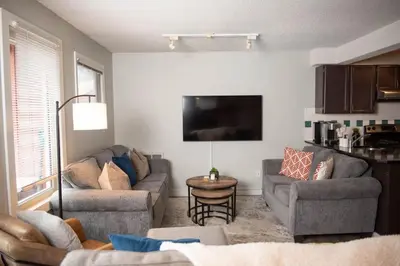 a living room with two couches and a flat screen tv at Moguls, Lofted Ski in Ski Out with Hot Tub Access in Panorama