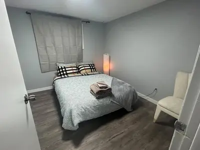 a bedroom with a bed and a chair at Cute Highlandpark (Lower B Unit) in Calgary