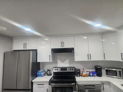 a kitchen with white cabinets and a stainless steel refrigerator at Cozy Basement Suite - private entrance - Free Netflix in Edmonton