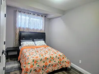 a bedroom with a bed with an orange bedspread and a window at Cozy Basement Suite - private entrance - Free Netflix in Edmonton