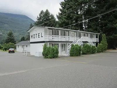 a white building with a sign on the side of it at The Mighty Fraser Motel in Boston Bar