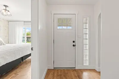 a white bedroom with a bed and a white door at Stunning Heritage Home, Sleep 8, Hot Tub, Private Yard, Firepit in Vernon