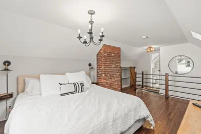 a bedroom with a white bed and a brick wall at Stunning Heritage Home, Sleep 8, Hot Tub, Private Yard, Firepit in Vernon