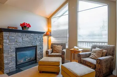 a living room with two chairs and a fireplace at Thunder Ridge Chalet by Fernie Lodging Company in Fernie