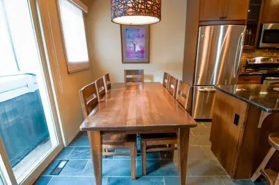 a kitchen with a wooden table with chairs and a refrigerator at Thunder Ridge Chalet by Fernie Lodging Company in Fernie