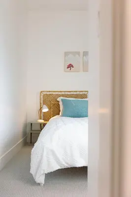 a white bedroom with a bed with a blue pillow at Revelstoke Alpine Retreat - RARE One-Bedroom Condo in Revelstoke