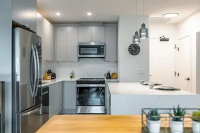 a kitchen with white cabinets and stainless steel appliances at Revelstoke Alpine Retreat - RARE One-Bedroom Condo in Revelstoke