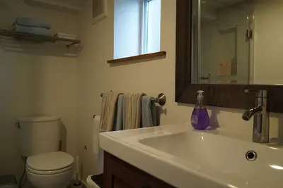 a bathroom with a sink and a toilet and a mirror at Private Suite Steps to Main St. in Vancouver