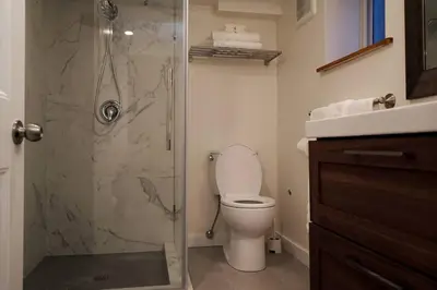 a bathroom with a toilet and a glass shower at Private Suite Steps to Main St. in Vancouver