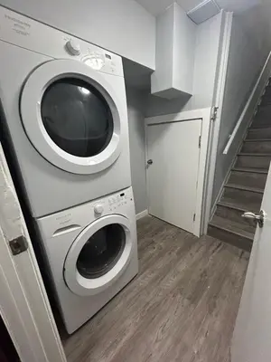 a laundry room with a washing machine and a staircase at Cute Highland Park Entire Unit A in Calgary