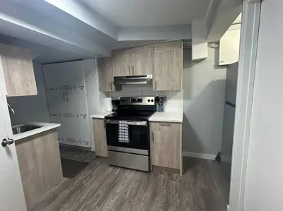 a small kitchen with wooden cabinets and a stove at Cute Highland Park Entire Unit B in Calgary
