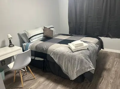 a bedroom with a bed with a desk and a chair at Cute Highland Park Entire Unit B in Calgary