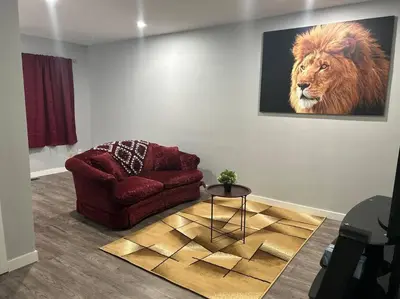 a living room with a red chair and a lion painting at Cute Highland Park Entire Unit B in Calgary