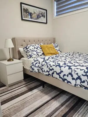 a bedroom with a bed with a blue and white comforter at Trendy 2-Bed Oasis Awaits! in Calgary