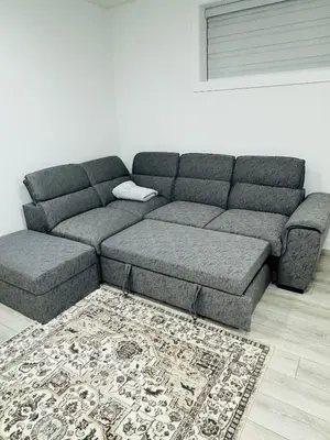 a gray couch in a living room with a rug at Angie’s place in Calgary