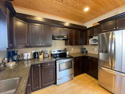 a kitchen with wooden cabinets and stainless steel appliances at Morrisey Chalet at Sun Peaks in Sun Peaks