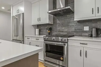 a kitchen with a stainless steel stove and white cabinets at Brand New - TimberLodge Spacious 2br in Canmore