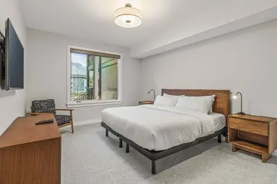 a bedroom with a bed and a desk and a window at Brand New - TimberLodge Spacious 2br in Canmore