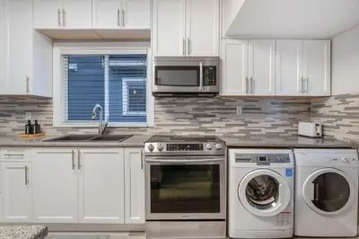 a kitchen with white cabinets and a washer and dryer at La Maison in Vancouver