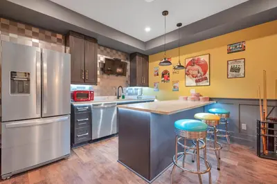 a kitchen with a stainless steel refrigerator and bar stools at Vi Cottage in North Saanich