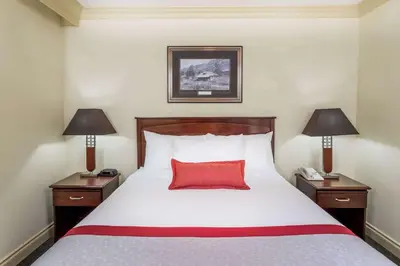 a bedroom with a bed with a red pillow and two lamps at Ramada by Wyndham Hinton in Hinton