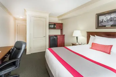 a hotel room with a bed and a desk and a chair at Ramada by Wyndham Hinton in Hinton