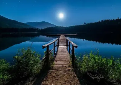a dock on a lake with the moon in the sky at The Mountain Loft in Canmore