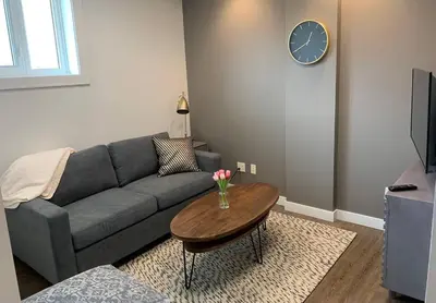 a living room with a couch and a table with a clock at The Mountain Loft in Canmore