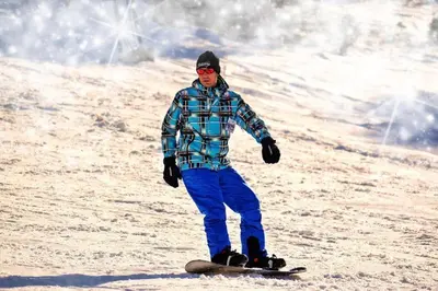 a man riding a snowboard down a snow covered slope at Mountain Modern Hideaway in Canmore