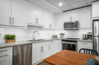 a kitchen with white cabinets and a wooden table at Mountain Modern Hideaway in Canmore