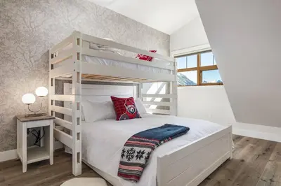 a white bedroom with a bunk bed with a ladder at The Grand Escape Downtown Canmore in Canmore