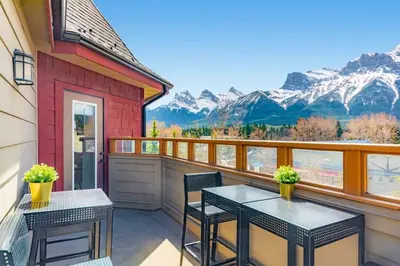 two tables and chairs on a balcony with mountains at The Grand Escape Downtown Canmore in Canmore