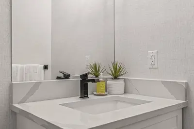 a white bathroom with a sink and a mirror at Mountain Vista Escape Downtown in Canmore