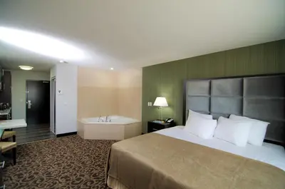 a hotel room with a bed and a bath tub at Paradise Inn and Suites Redwater in Redwater
