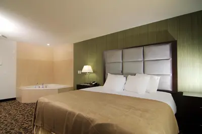 a hotel room with a large bed and a bath tub at Paradise Inn and Suites Redwater in Redwater