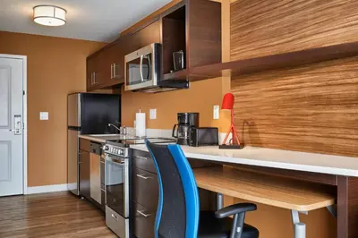 a kitchen with a counter and some blue chairs at TownePlace Suites by Marriott Fort McMurray in Fort McMurray