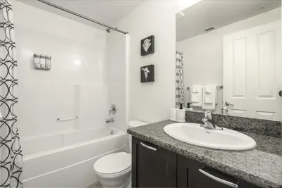 a white bathroom with a sink and a toilet at UC Stampede Condo by Train, Hospital, free UG parking & Gym, AC, full kitchen in Calgary
