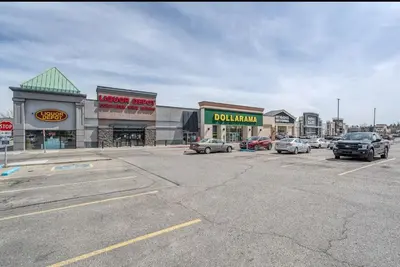 a parking lot with cars parked in front of buildings at UC Stampede Condo by Train, Hospital, free UG parking & Gym, AC, full kitchen in Calgary