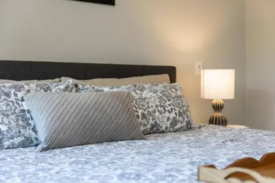 a bedroom with a bed with a pillow and a lamp at Kelowna family-friendly lake & Mountain view Luxury condo with AC, pool, Hot tub, near winery and shopping center in West Kelowna