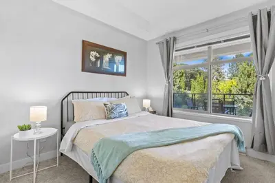 a white bedroom with a bed and a window at Kelowna family-friendly lake & Mountain view Luxury condo with AC, pool, Hot tub, near winery and shopping center in West Kelowna
