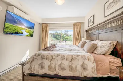 a bedroom with a large bed with a large window at Top Floor Lakeview Condo at Copper Sky 509 in West Kelowna