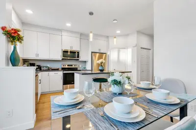 a kitchen with white cabinets and a dining table with chairs at Your Happy Place Seton3 bed. Sleeps 6. 2.5bath in Calgary