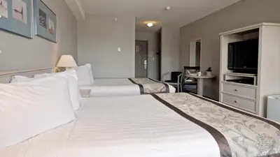 a hotel room with two beds and a television at Quarterdeck Inn Port Hardy in Port Hardy