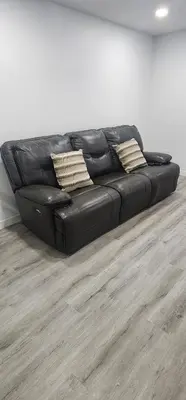 a black leather couch sitting in a living room at Cozy One bedroom BSMT Apartment in Edmonton