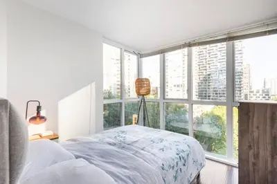 a bedroom with a bed and a large window at Luxury 2-bedroom condo beach side Yaletown in Vancouver