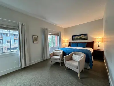 a bedroom with a bed and two chairs and a window at Mountain Retreat Corner Suite -Pool - Hot Tub & Spa Escape in Canmore