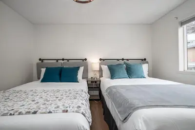 two beds in a white room with blue pillows at Luxurious Retreat/Hot Tub/Mountain View/4 Beds in Canmore